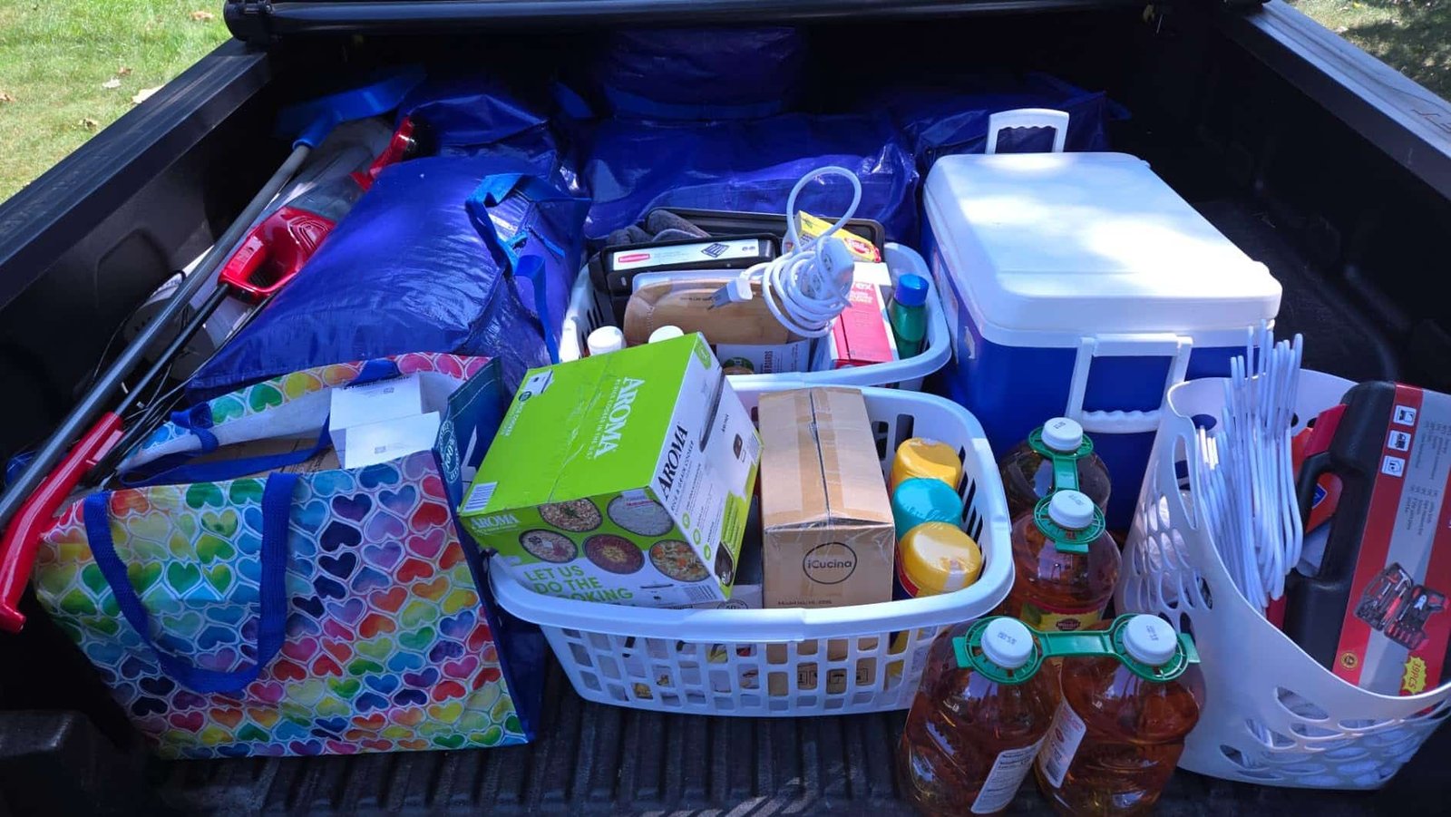 Packed truck bed with storage bins, reusable bags, and supplies for transport