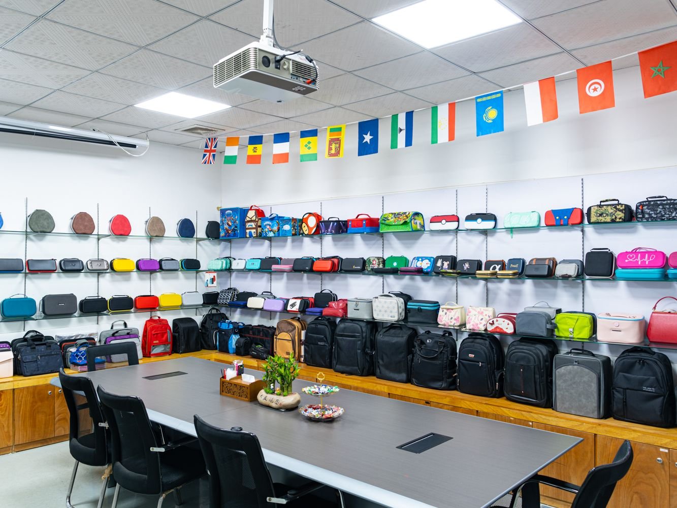 Showroom displaying various colorful bags and backpacks with international flags above