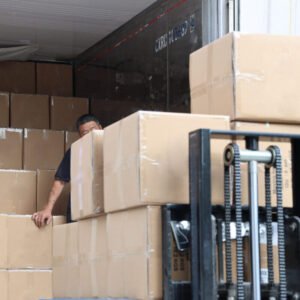 Workers loading packed boxes of custom canvas tote bags into a shipping container for international delivery