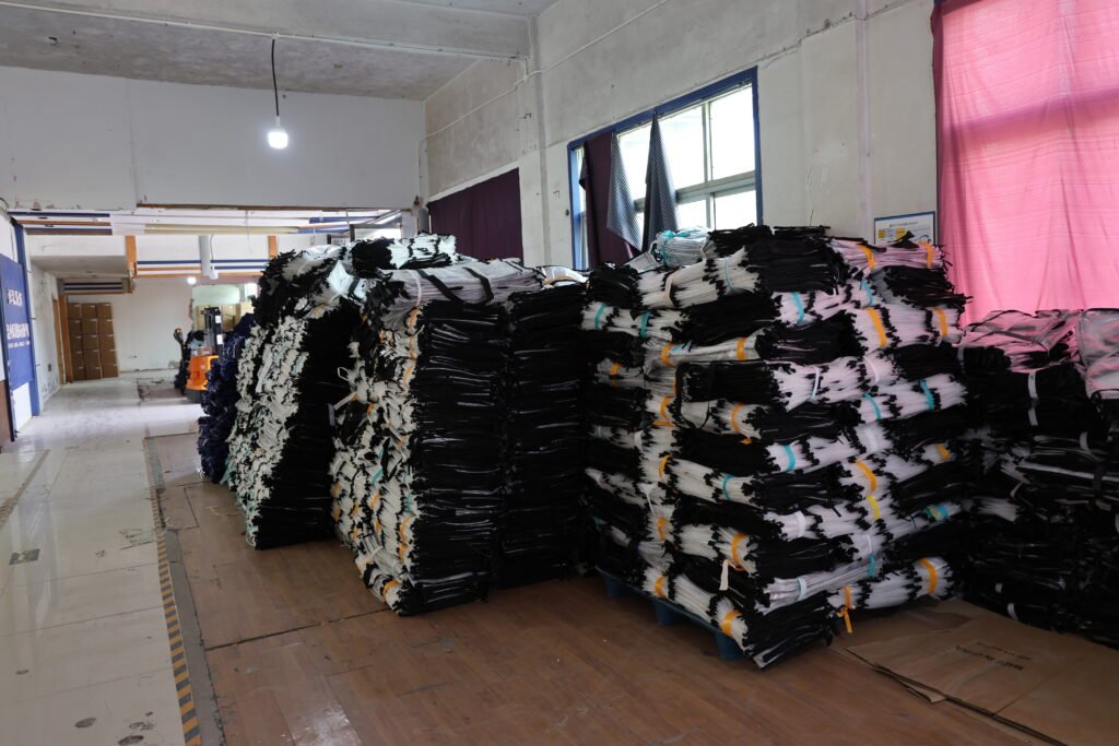 Bulk stacks of black insulated delivery bags in a warehouse, ready for packaging and shipment.