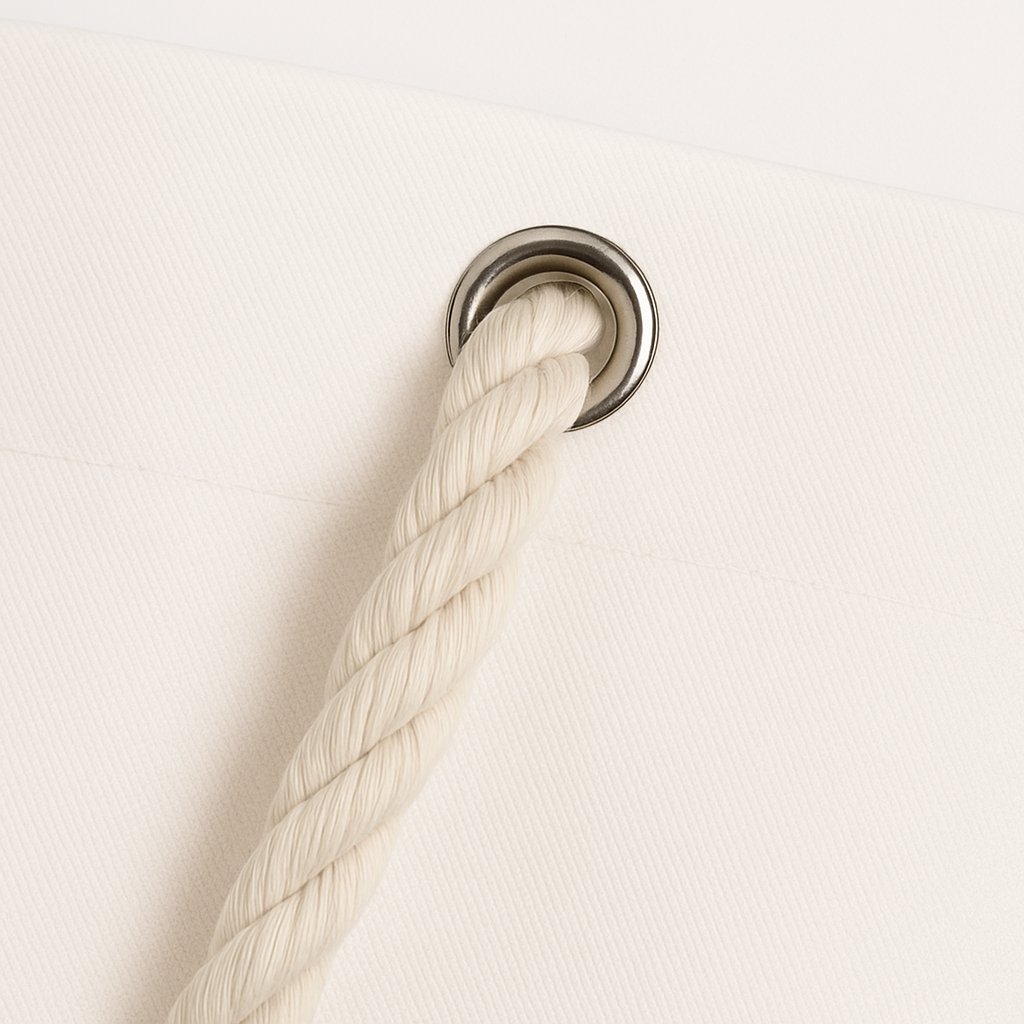 Heavy-duty rope handle threaded through metal grommet on canvas tote bag, designed for strength and comfort