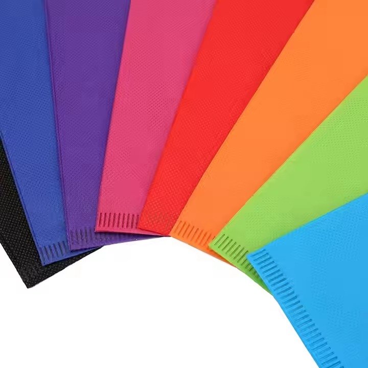 Assorted colorful non-woven fabric material samples in multiple shades, ideal for making reusable tote bags and custom packaging products.