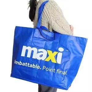 Large blue reusable shopping tote bag with printed Maxi logo, carried on shoulder, ideal for retail, grocery shopping, and promotional use.