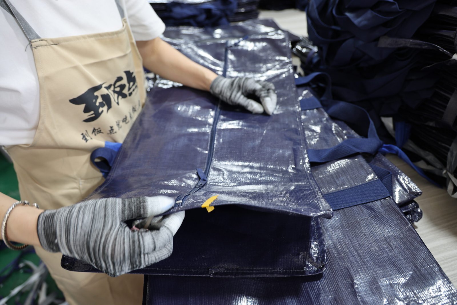 Worker performing quality inspection on navy blue moving bag in production line