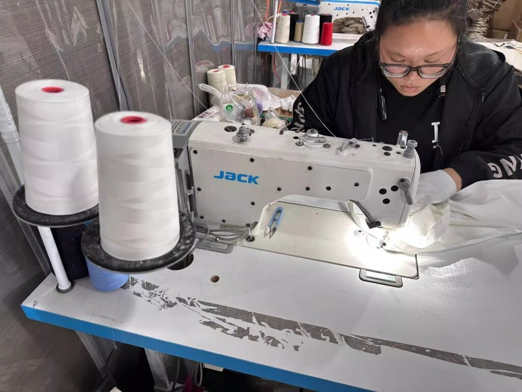 Female technician precisely stitching canvas tote bag during manufacturing process