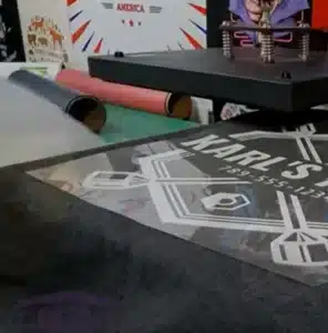 Heat transfer printing machine applying graphic design on shopping bag material.
