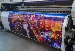Large-format printer producing colorful custom designs on reusable bag fabric.