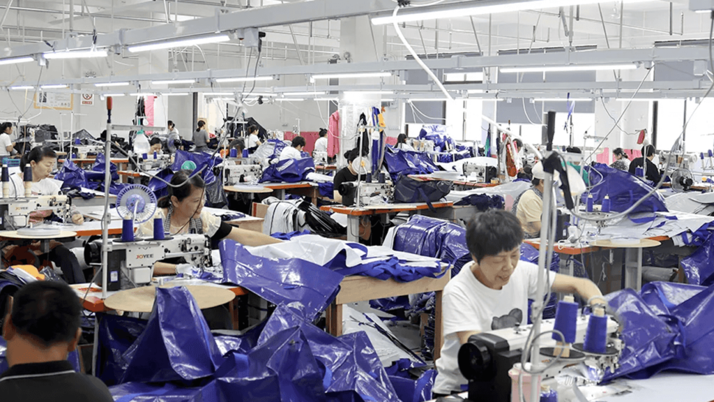 Factory workers assembling heavy-duty moving bags in a large-scale production workshop