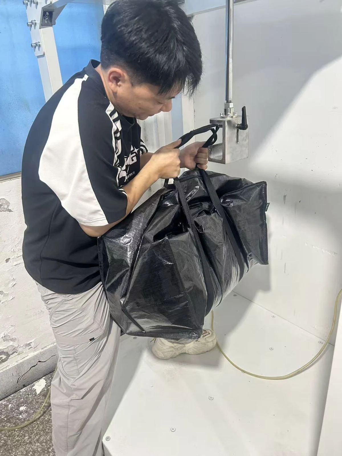 Moving Bags Manufacturing Tiiocti Technician Positioning The Black Moving Bags Handle Straps On The Oscillation Test Attachment