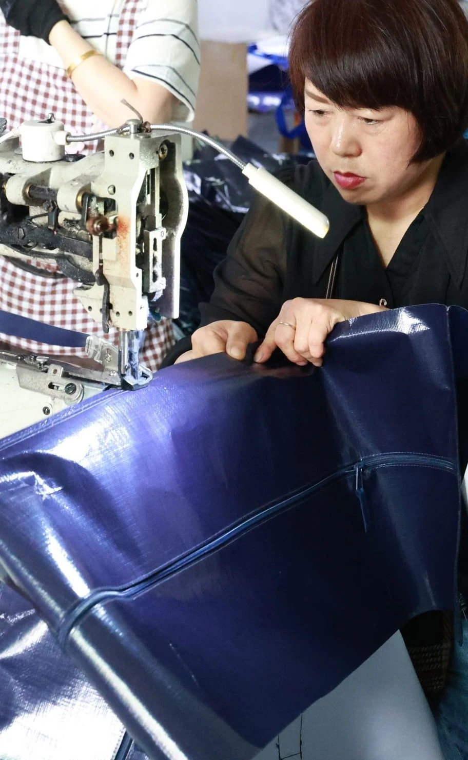 Moving Bags Manufacturing Tiiocti Worker Guiding Blue Moving Bag Material Through An Industrial Sewing Machine Beside The Zipper Seam