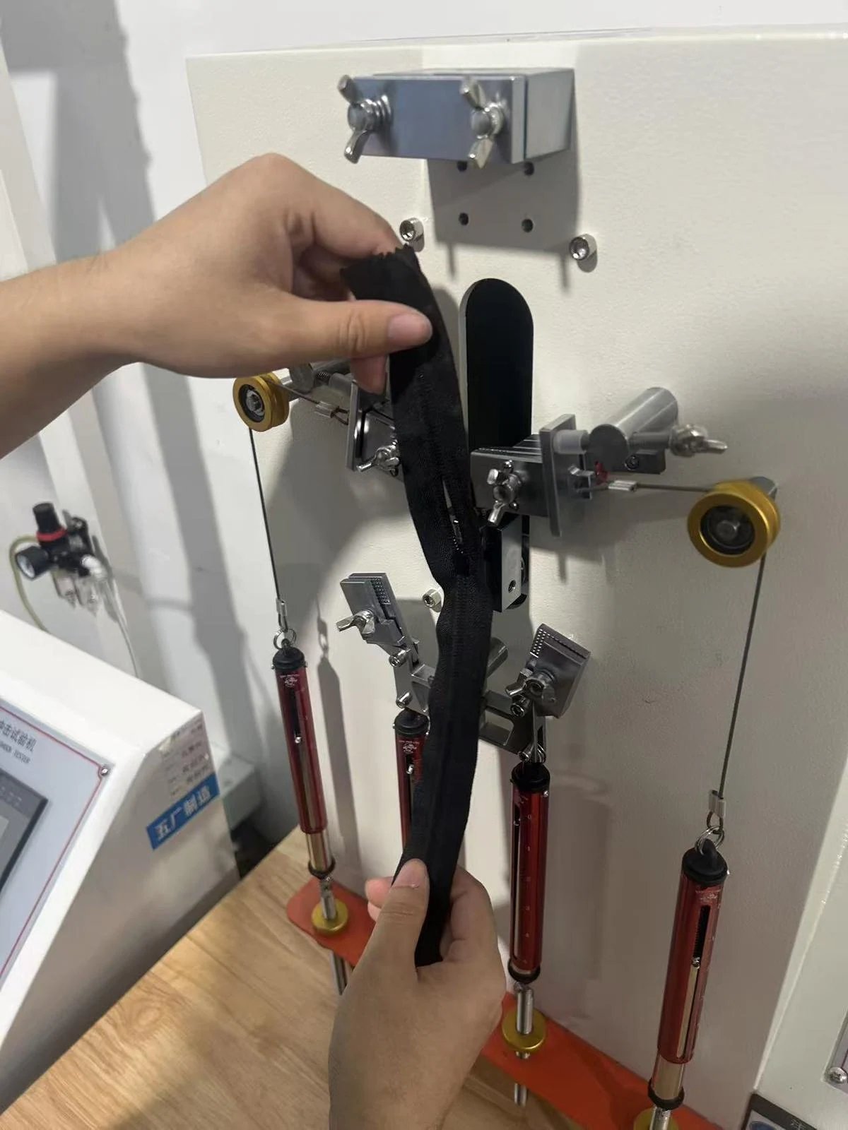 Moving Bags Manufacturing Tiiocti Hands Positioning A Black Zipper Sample In The Clamps Of The Zipper Testing Machine