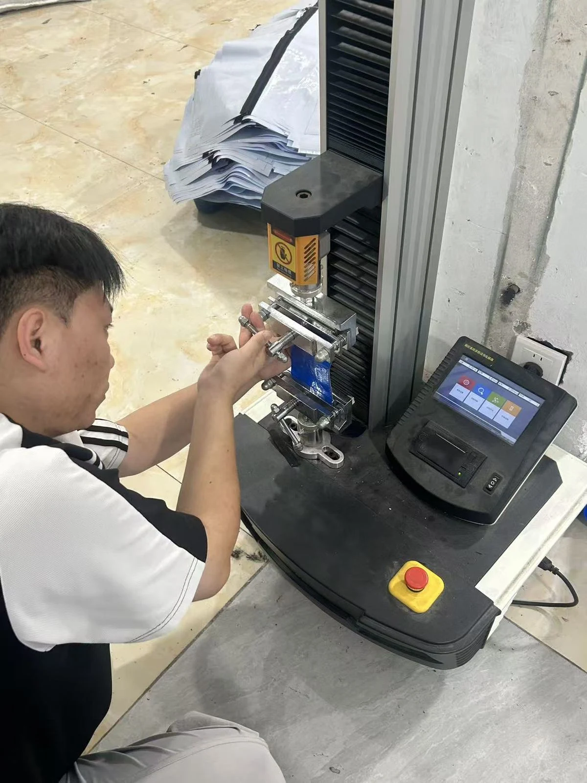 Moving Bags Manufacturing Tiiocti Technician Securing A Blue Bag Material Sample In The Tensile Testing Machine