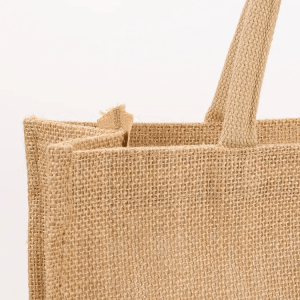 Side profile of plain jute shopping tote bag with sturdy white handles
