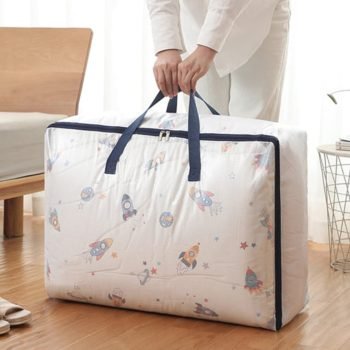 Person holding a large rocket-print moving bag with navy handles, ideal for comforter or blanket storage