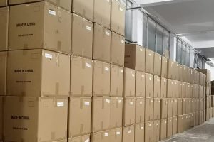 Storage area with large stacked cardboard boxes filled with wholesale custom canvas tote bags