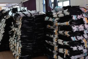Bulk stacks of black insulated delivery bags in a warehouse, ready for packaging and shipment.