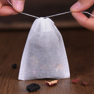 Small white drawstring filter tea bag filled with dried tea leaves and herbs, ideal for brewing loose leaf tea or herbal infusions.