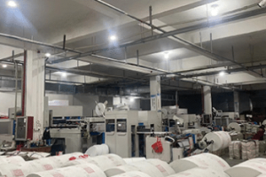 Factory workshop with production machines and raw materials for manufacturing insulated delivery bags.