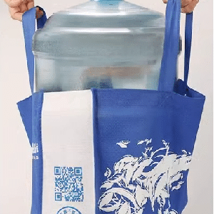 Blue reusable heavy-duty tote bag carrying a large water bottle, printed with custom white logo and QR code, ideal for promotional and daily use.