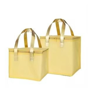Two gold insulated cooler bags with matching handles Set of two yellow reusable insulated lunch tote bags with gold handles, ideal for food delivery, grocery shopping, and thermal preservation.