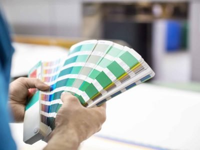 Close up of man hands with color samples at printing press. Cropped shot  male graphic designer with color swatch.